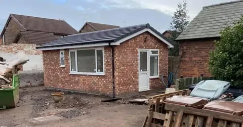 Brick outbuilding under construction with the new roof structure in place