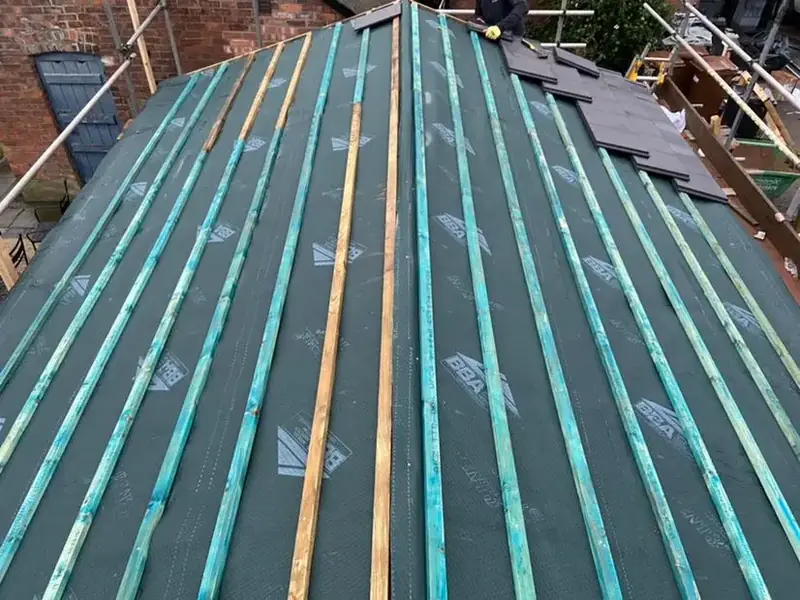 Pitched roof covered in breather membrane with battens being fixed