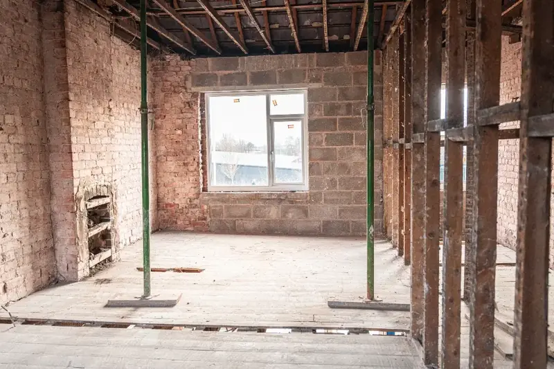 Interior stripped back to blockwork and propped, with a new window opening formed