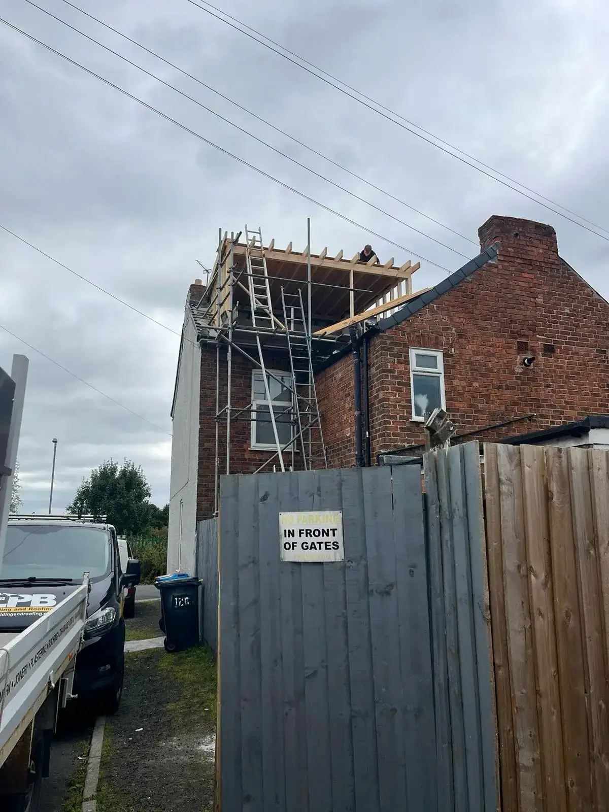 House under scaffold with roof works in progress and materials on site